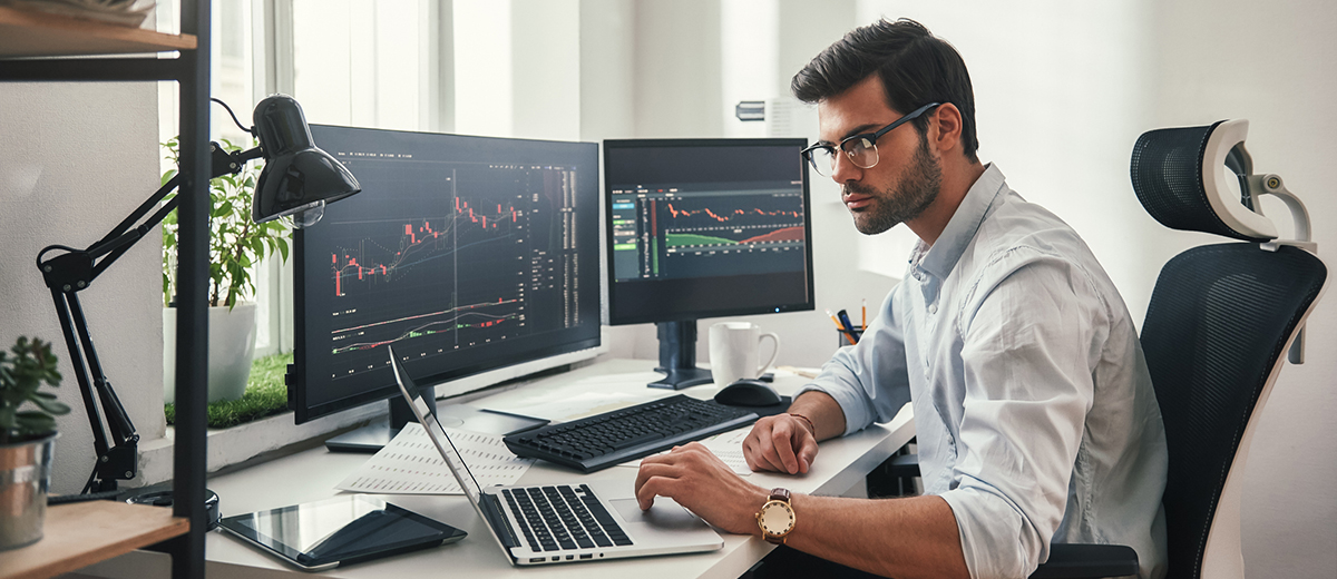 Man at desk looking at stock charts on his computer.