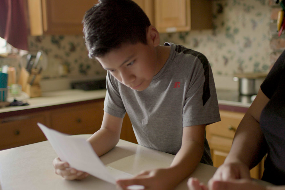 Photo of boy reading document for parent