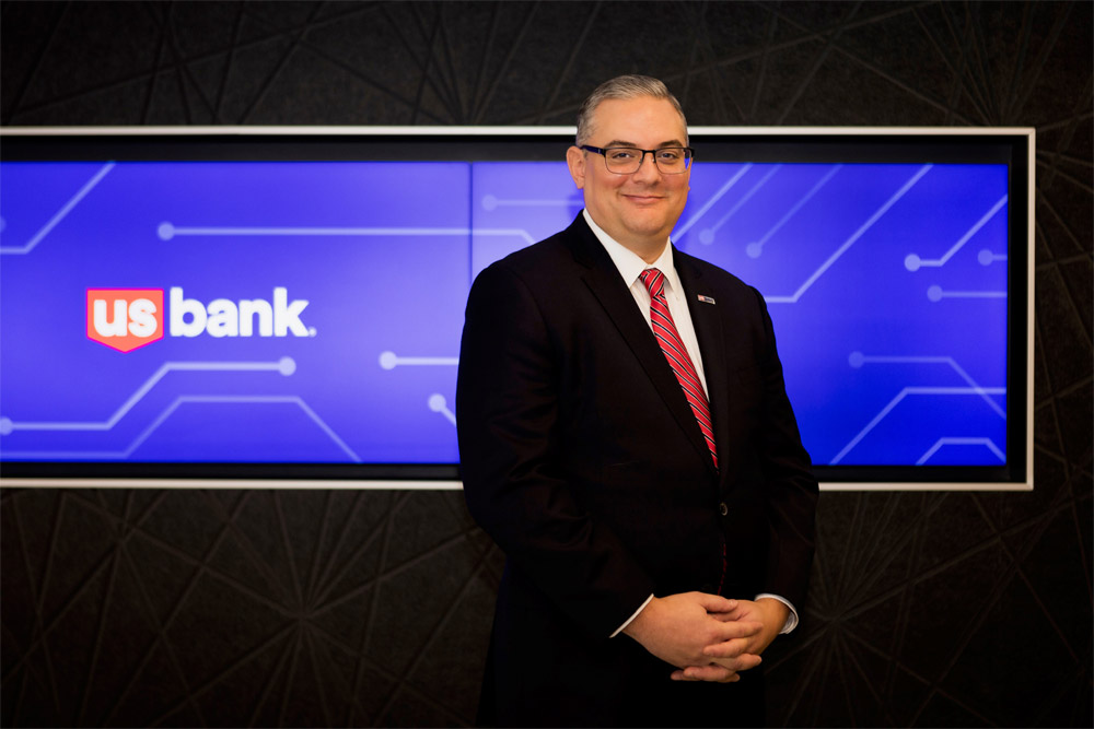 Photo of man in suit standing in front of security sign