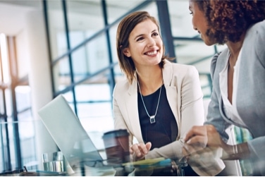 Two people sitting at a conference table talking to each other 