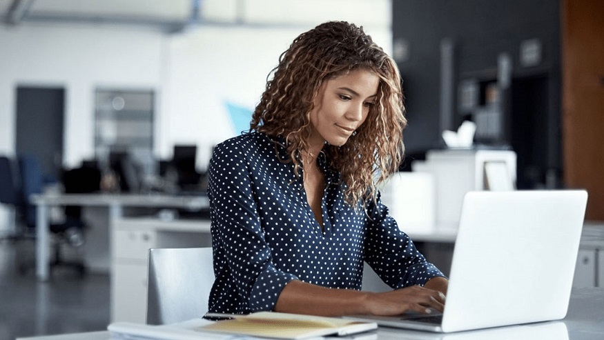 Woman in an office using her laptop to wire money overseas