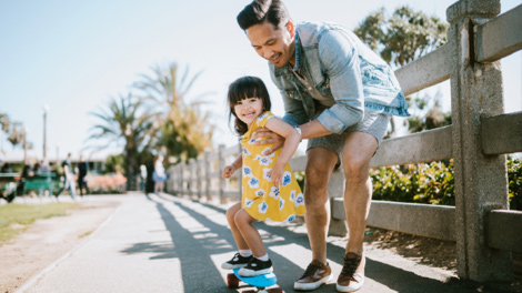 Father teaching daughter to skateboard