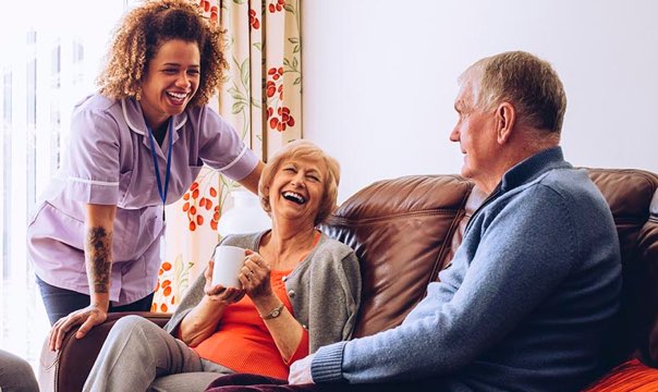 Caregiver laughing with husband and wife