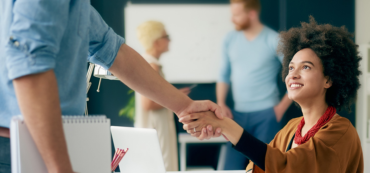 Young Black woman shaking hands with a man who is out of frame