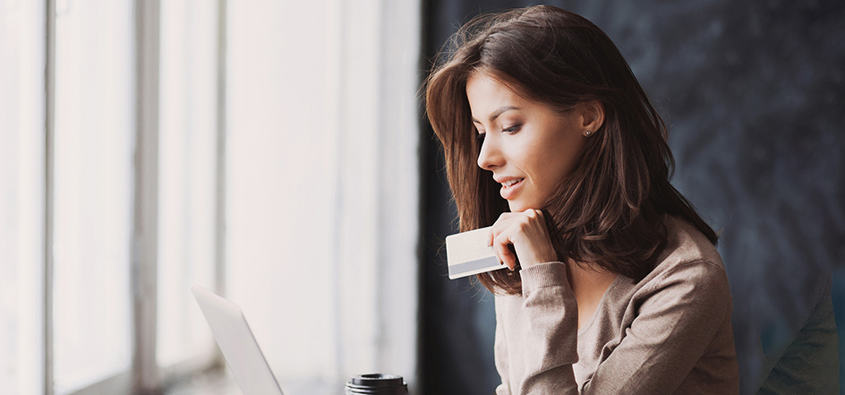 woman holding a credit card looking at a laptop