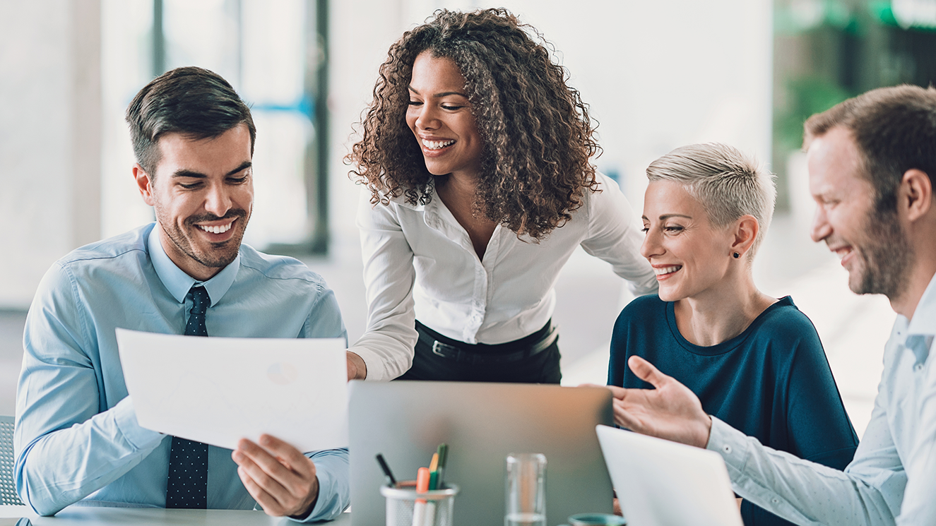 Two women and two men dressed in formal attire and working together, looking at paperwork and gesturing as they research global fund services.