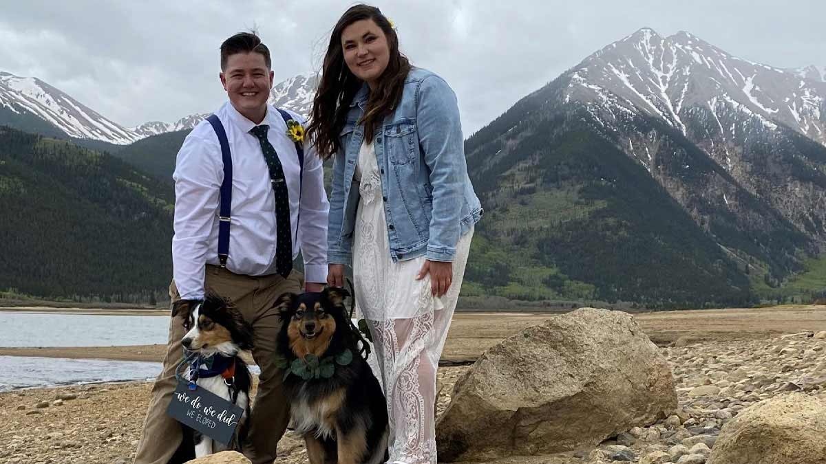 Man, woman and two dogs in front of mountains