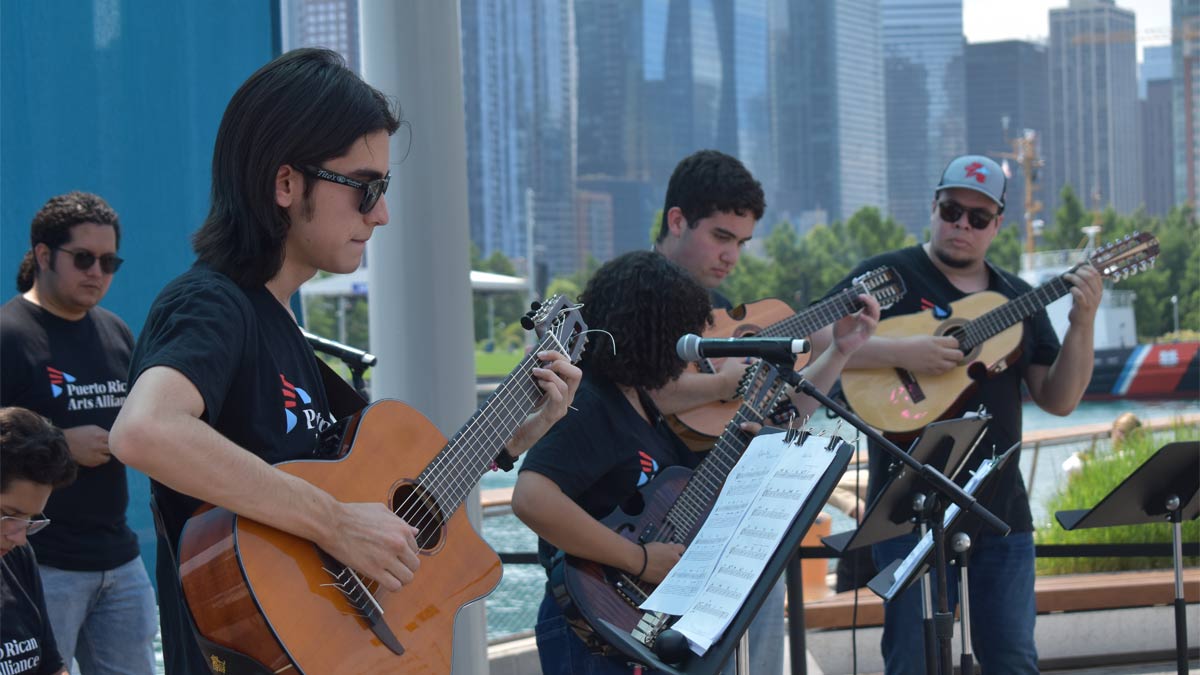 People playing guitar outside on a stage