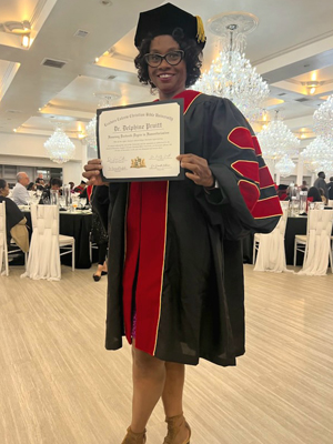 Photo of woman in graduation attire holding a degree