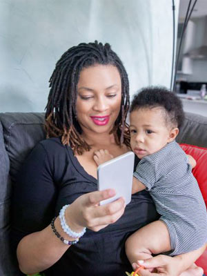 Woman looking at phone while holding child