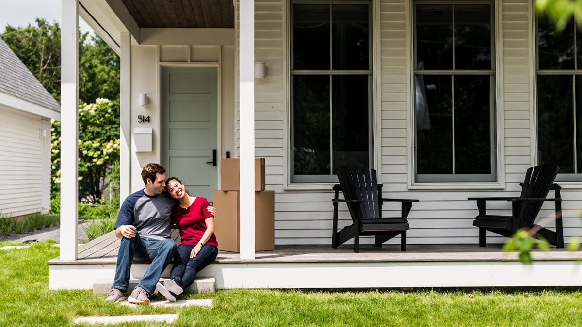 Man and woman sitting on the front porch of a house.