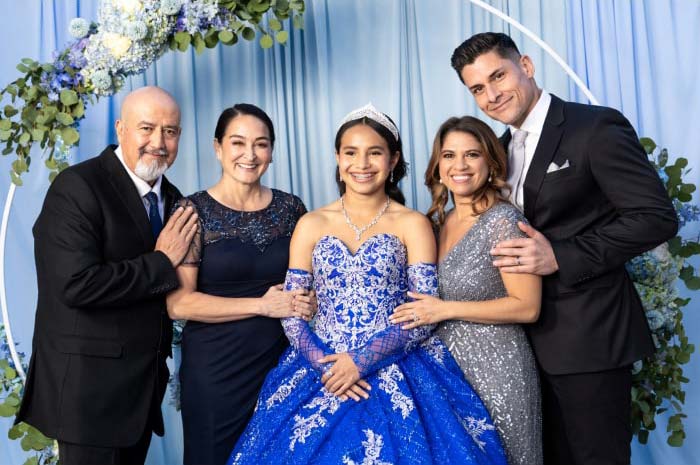 Three generations of a Hispanic family pose for a picture at a young woman’s Quinceanera party.