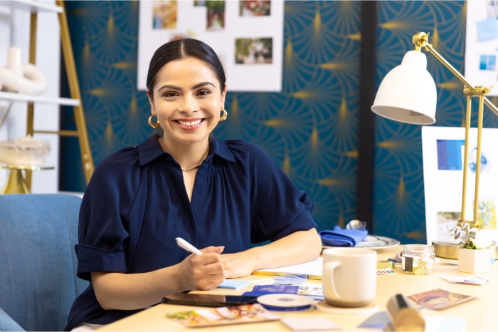 A young Hispanic business owner smiles at her desk.