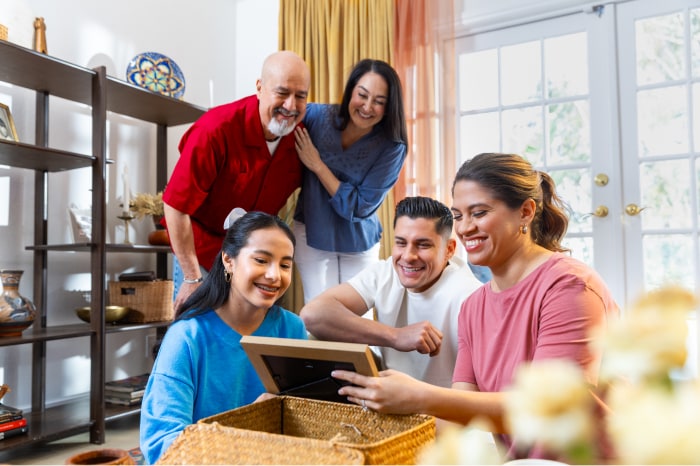 A Hispanic family unpacks a box and looks at a photo together.