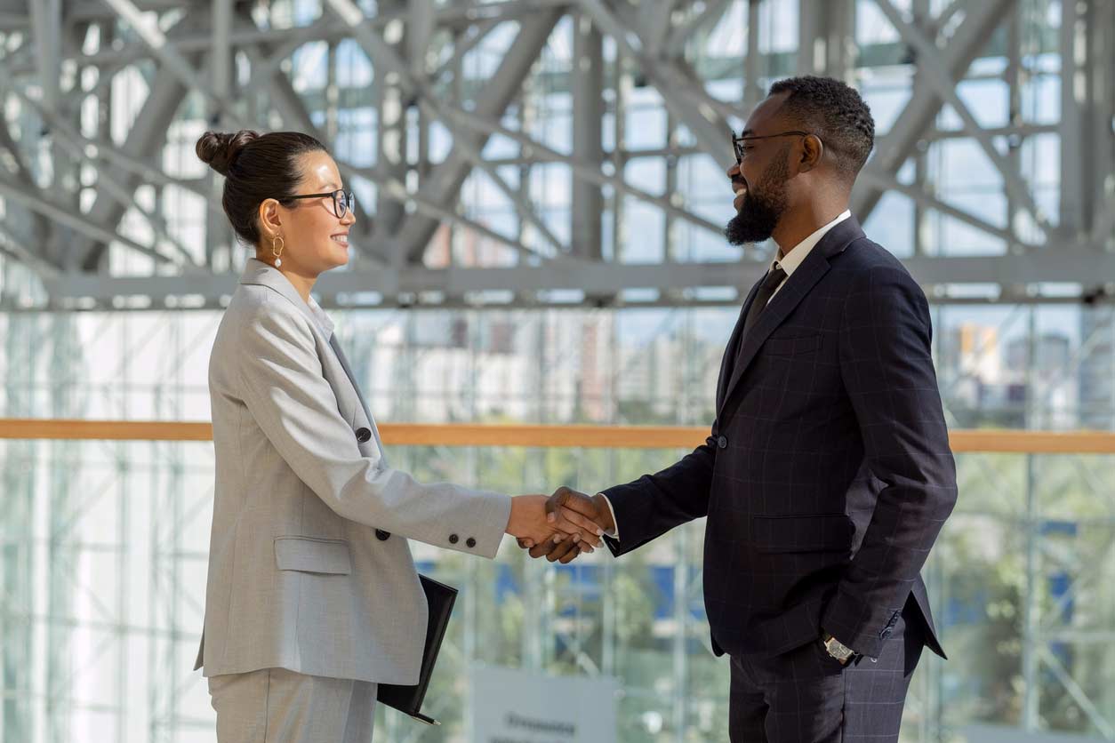 Professional woman and man shaking hands outside a business meeting