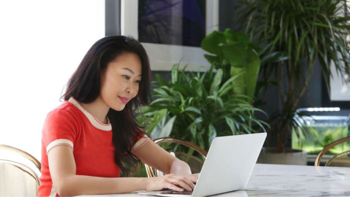 Photo of a woman in a red shirt on her laptop